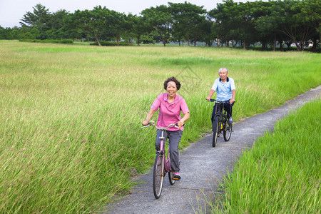 快乐的亚洲老年人夫妇在公园里骑自行车退休和健康的图片