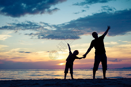 日落时父子在海滩上玩耍幸福友好家庭的概念图片