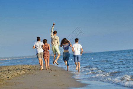 快乐的年轻人群体有乐趣跑步和跳跃在日图片