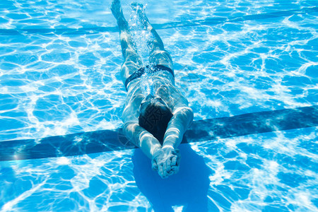 年轻人在水下游泳在游泳池里潜水然图片