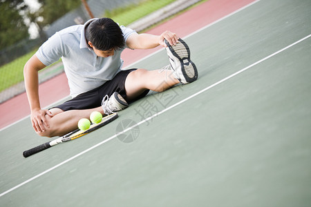 一名亚洲男子网球运动员在比赛前伸展身体图片