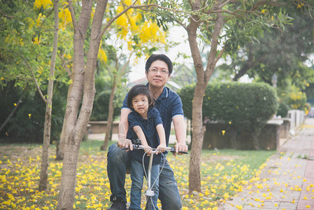 快乐的亚洲父亲和儿子骑自行车图片