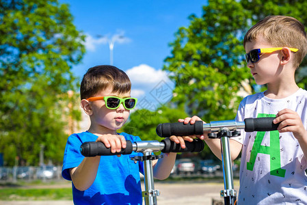 两个小男孩骑着推车警告暑假或春日兄弟男孩一起玩得开心戴着墨镜图片