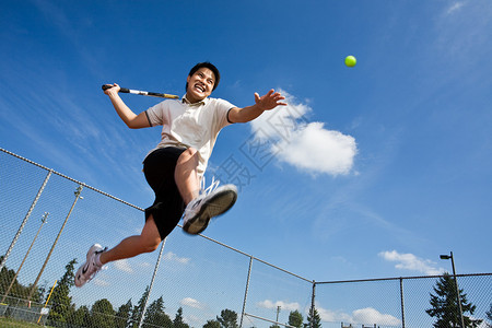 一个亚洲网球运动员在空中跳跃图片