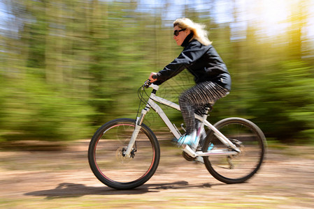 在森林路上骑着山地自行车的女人图片