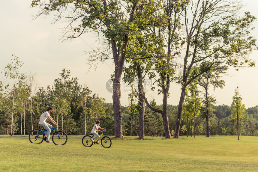 对年轻父亲和他的小儿子穿着便衣在公园骑脚踏图片