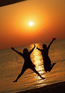 两个女孩跳上黎明太阳的背景专注于模特儿浅的田地深处图片