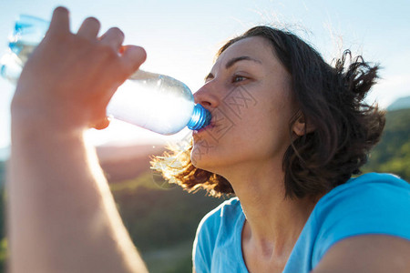 一个女人在山顶喝水女孩解渴疲惫的游客用塑料瓶喝饮料黑发女人嘴图片