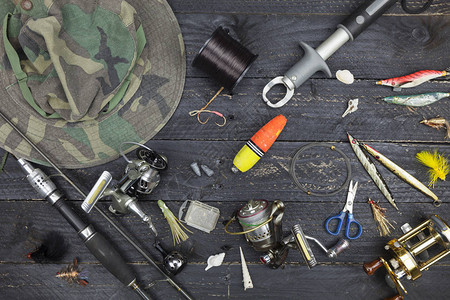 钓鱼竿和卷轴黑色木质背景上的渔具图片