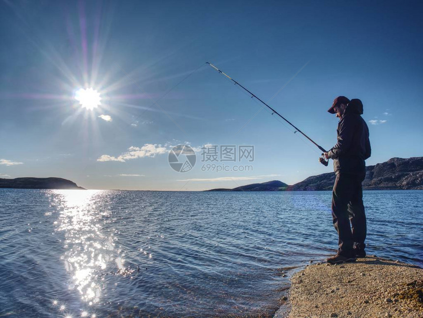 年轻男子在时在湖边捕鱼图片