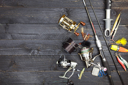 钓鱼竿和卷轴黑色木质背景上的渔具背景图片