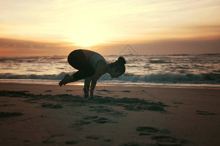 在海滩做瑜伽练习的运动型年轻女健康生活理念和身心发展之图片