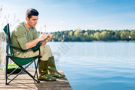 在湖边钓鱼的人用钓竿固定诱饵图片