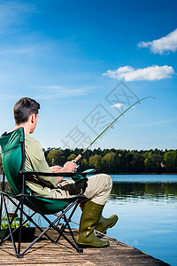 在湖边钓鱼的人坐在离图片