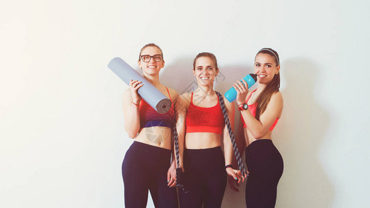 韩式美型靠墙站立的型年轻女体育背景三个健身女孩在健身房锻炼后复制空间在健身房里穿着服的女健身健康背景