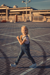微笑的可爱孩子手里拿着滑板走路在停背景图片