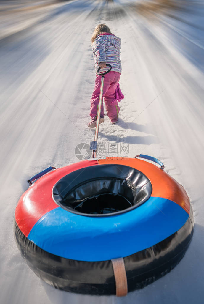 小女孩在滑下雪冰的山坡后拉起她多彩图片