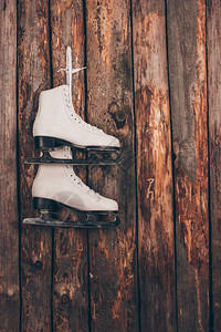 挂在破旧木墙上的一双白色溜冰鞋图片