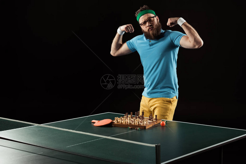 网球运动员显示肌肉同时站在网球桌旁象图片
