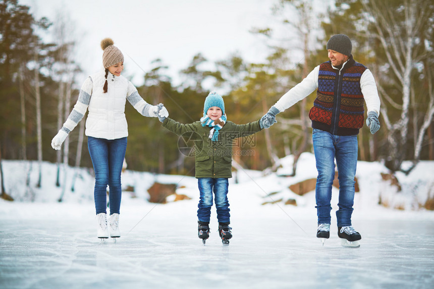 嬉戏的家庭在溜冰场上滑冰手牵图片