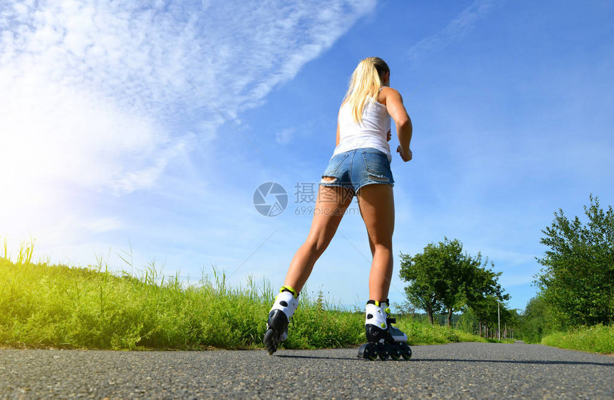 夏天穿旱冰鞋的少女路上的直排轮滑图片
