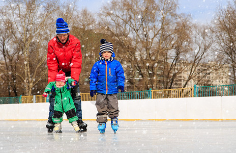 父亲和两个孩子在冬天滑冰图片