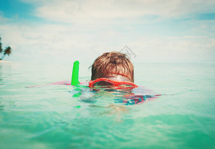 小男孩在海边戴着面具游泳图片
