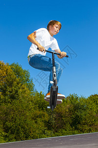男孩骑着他的滑板车跳跃图片