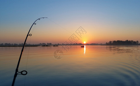 日出时在河岸上索具钓鱼竿图片