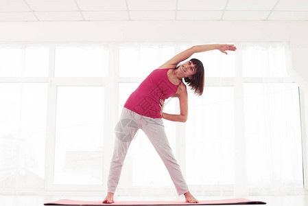 低角度的兴奋的女人站在健身房侧伸展打开位置并诱导平静的感觉站图片