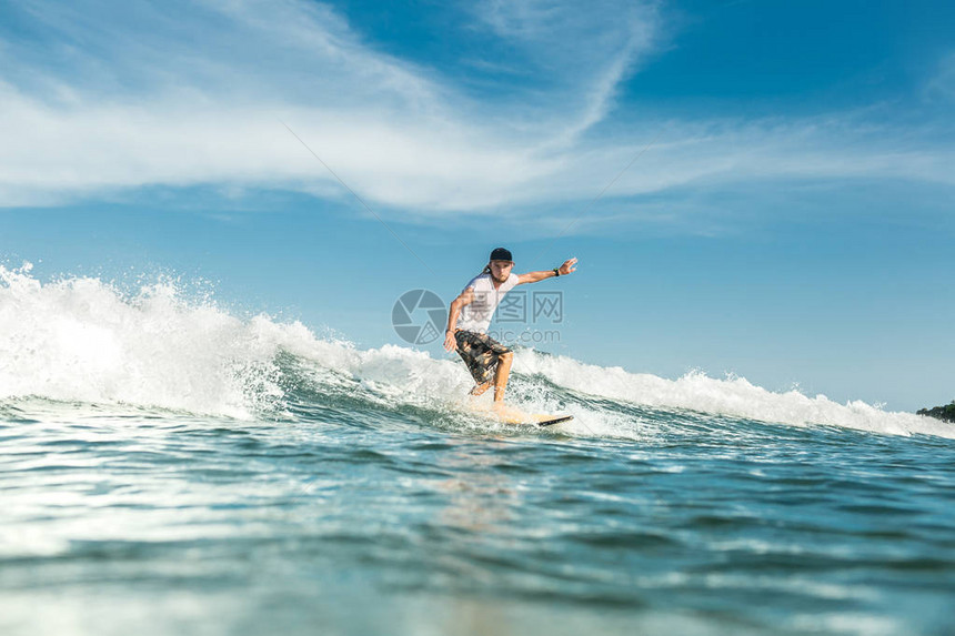 在印度尼西亚巴厘努沙杜阿海滩的海洋中骑着海浪的年轻图片