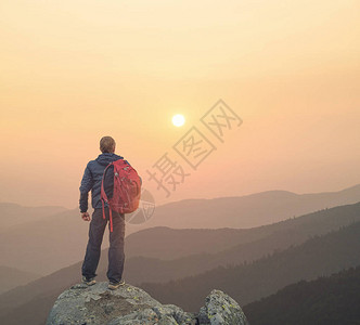 日落时高岩石峰顶上的旅游者体育和图片