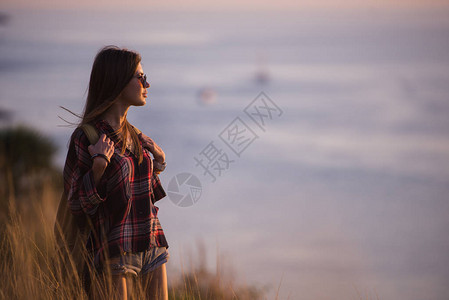 女旅行者在日落时看山湾的悬崖边缘图片