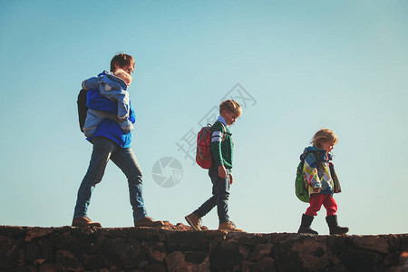 父亲和三个小孩在山上徒步旅行图片