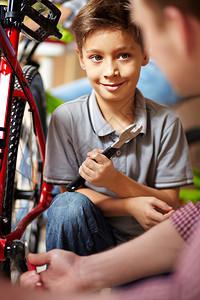 在车库修理自行车时看着他父亲的可图片