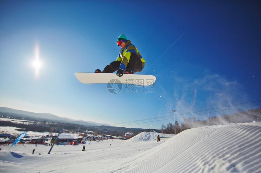 滑雪板的运动型男子飞越雪堆图片