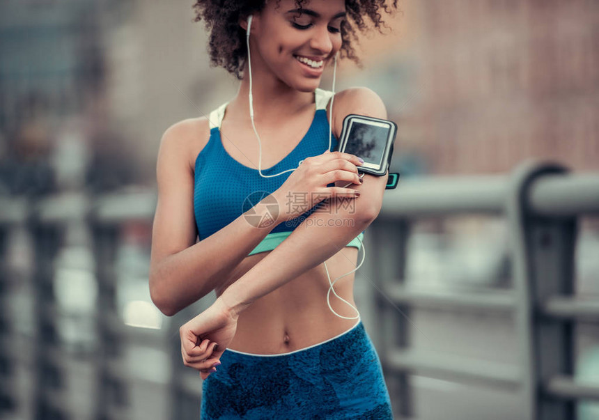 穿运动服和耳机的美籍黑人女孩使用智能手机图片