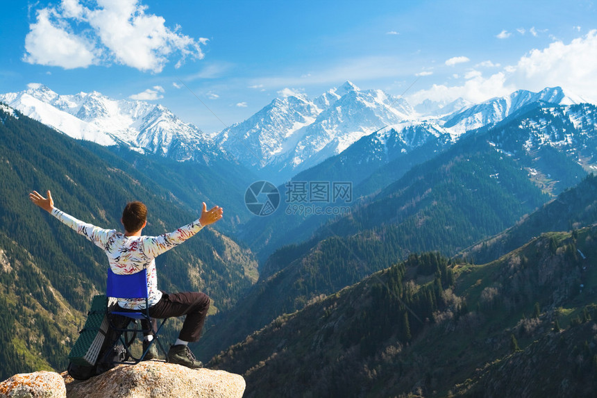 年轻人在山顶愉快地放松的形象他的目光瞄准了背景中一个非常大的山图片