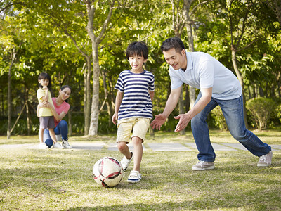 父亲教儿子在公园踢足球足球图片