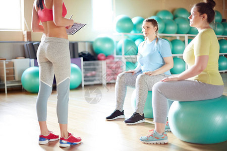 2个身穿运动服的女孩坐在健身球上图片