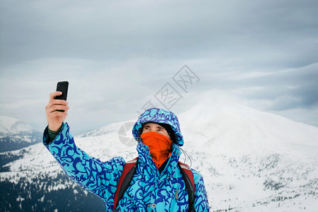 在山地背景上使用智能手机的自拍人户外活动在图片