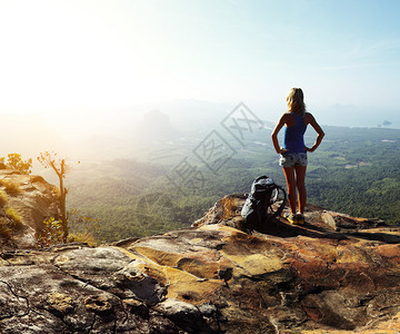 背着包站在山顶欣赏山谷景色的徒步旅行者图片