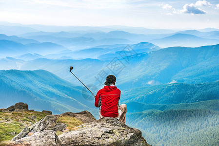 山顶的年轻男子用相机拍摄自图片