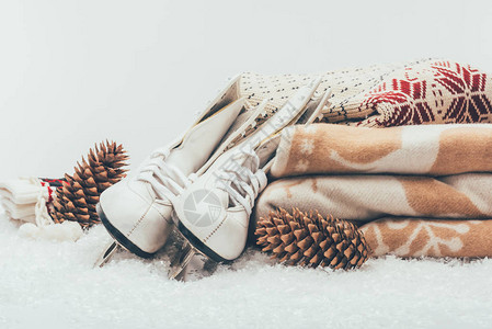 白色溜冰鞋配松果和一堆毯子和毛衣图片