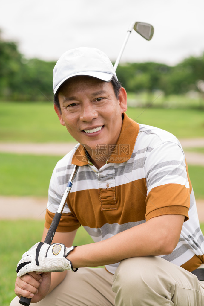 一个英俊高尔夫球手的垂直肖像和一个高尔夫铁在摄图片
