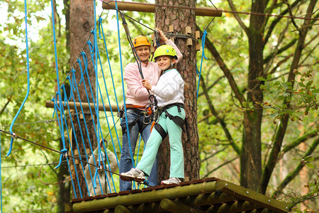 母亲和女儿在攀爬设备中以克服高树图片