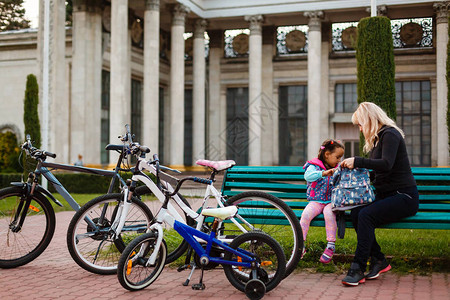 妈和她的小女儿坐在长凳上骑自行车图片