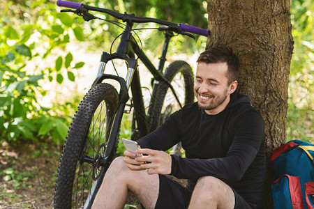 骑车在树下休息后快乐的男子图片