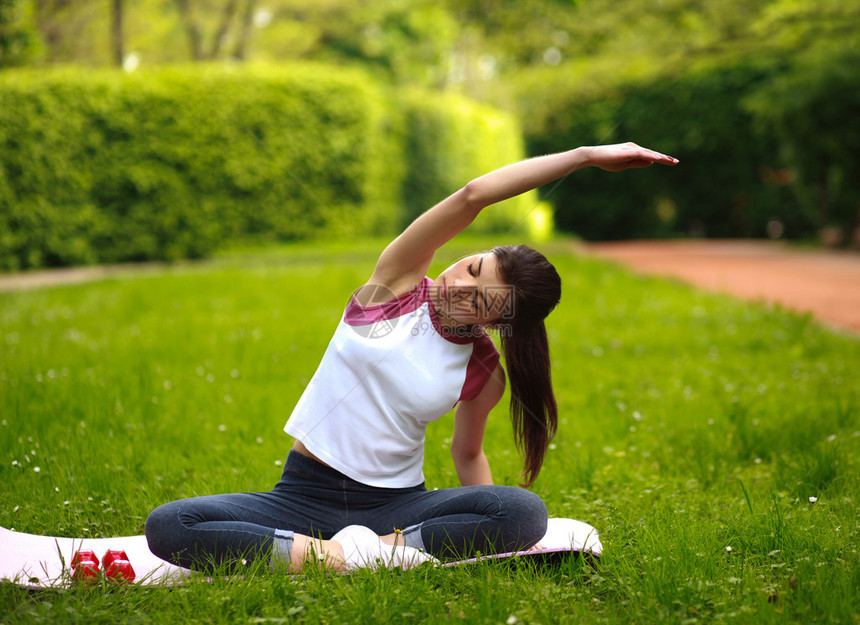 运动女青年在绿色公园拉伸健图片