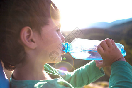 一个男孩从瓶子里喝水孩子解渴了孩子正在山间旅行疲倦的孩子图片